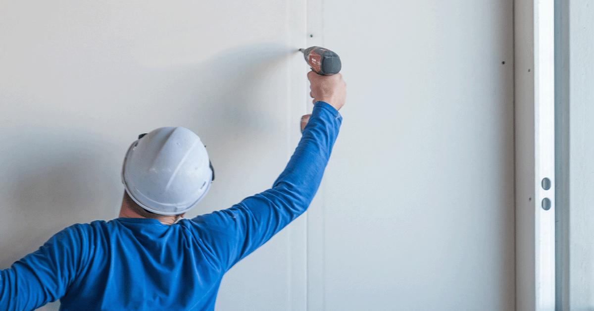 Commercial construction employee installing new drywall sheets