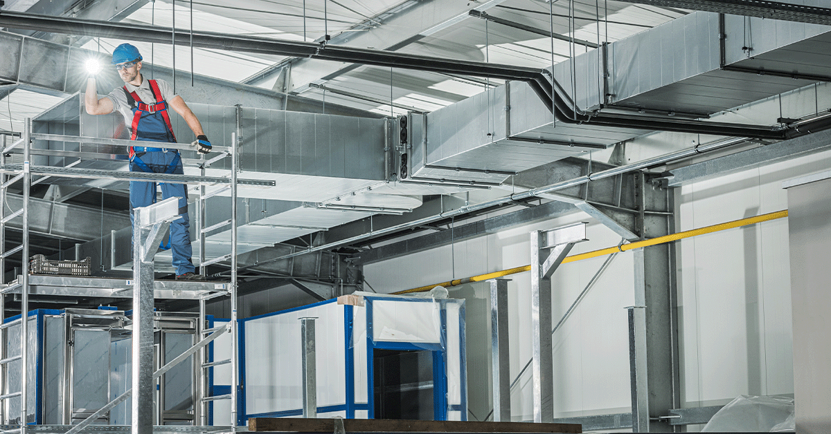 HVAC technician working with large air vents